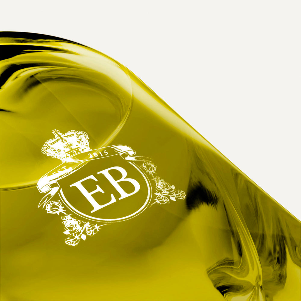 Detail of the bottom of the 250 ml bottle, with transparent glass and greenish perfum. Detail of logo with the EB initials in white ink. Apollo Hyacinth, a fragrance by Eric Butherbaugh.