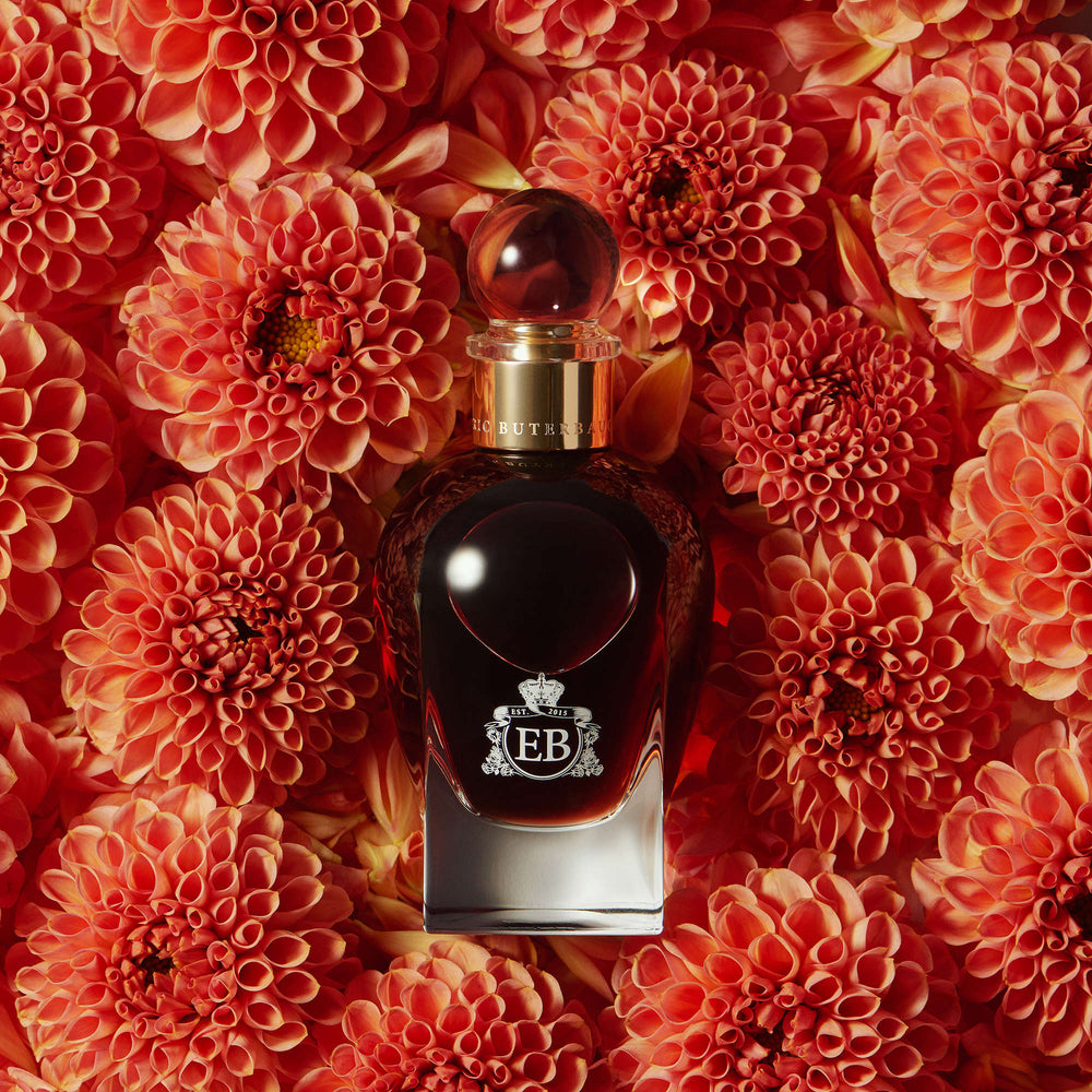 A 100 ml 1947 Dalhia bottle lying on a bed of orange dalhias.