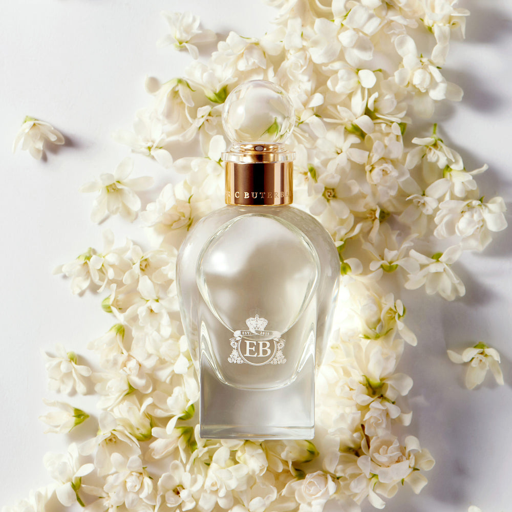 A 100 ml Kingston Osmanthus bottle lying on a bed of white osmanthus.