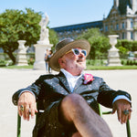 Eric Buterbaugh, wearing a hat and sitting, enjoying the sun.