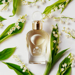 A 100 ml Virgin Lily of the Valley bottle lying next to some Lily of the Valley.