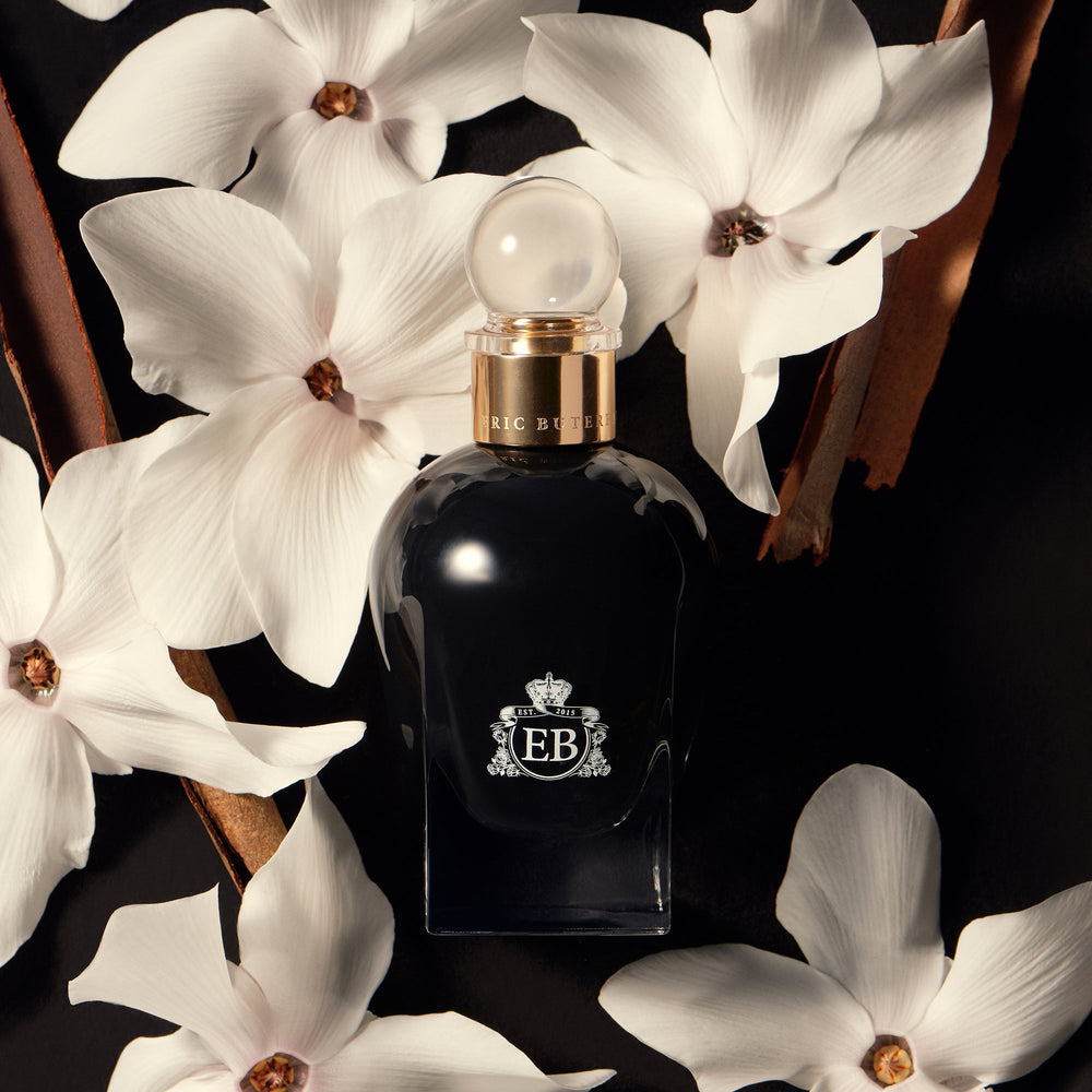 A 100 ml Oud Orange Flower bottle lying next to some orange blossoms.